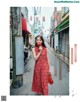 A woman in a red dress standing on a street.