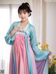 A woman in a blue and pink hanbok is posing for a picture.