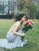 A woman sitting on the grass holding a bouquet of flowers.