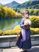 A woman in a blue kimono standing in front of a lake.