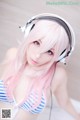 A woman with pink hair wearing headphones and a striped bikini.