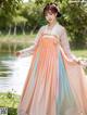 A woman in a pink and blue dress standing by a lake.