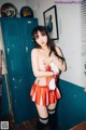 A woman in a cheerleader outfit posing in front of lockers.