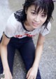 A young woman sitting on the ground with her legs crossed.