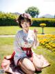 A woman in a kimono sitting on the grass in a park.