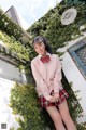 A young woman in a pink sweater and plaid skirt posing for a picture.