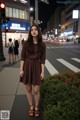 A woman standing in the middle of a city street at night.