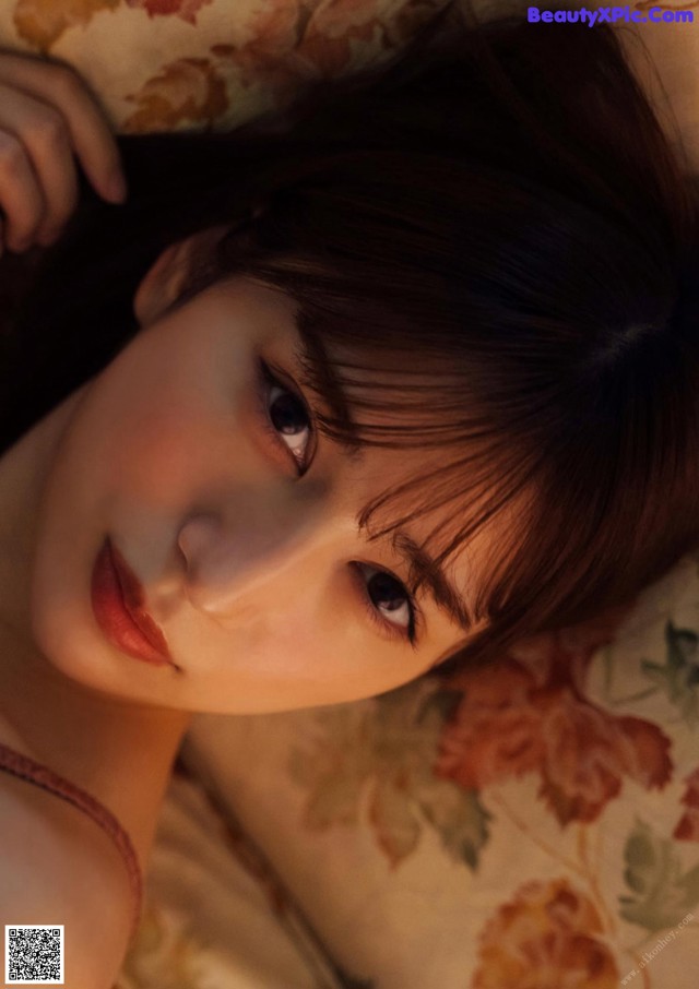 A woman laying on top of a bed next to a pillow.